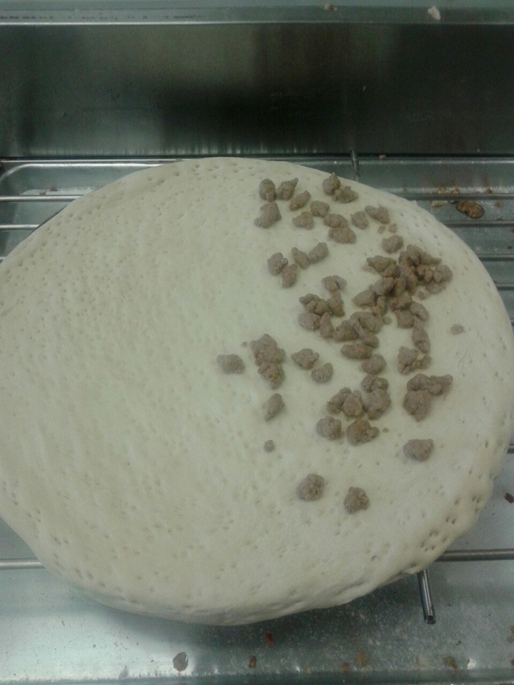 pizza crust with no toppings on the left, scattered sausage on the right